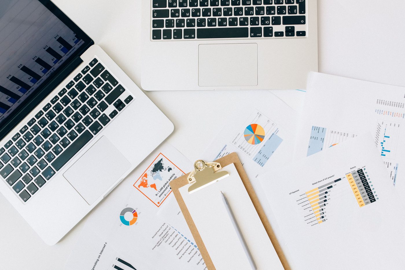 Financial reports and working papers beside a laptop